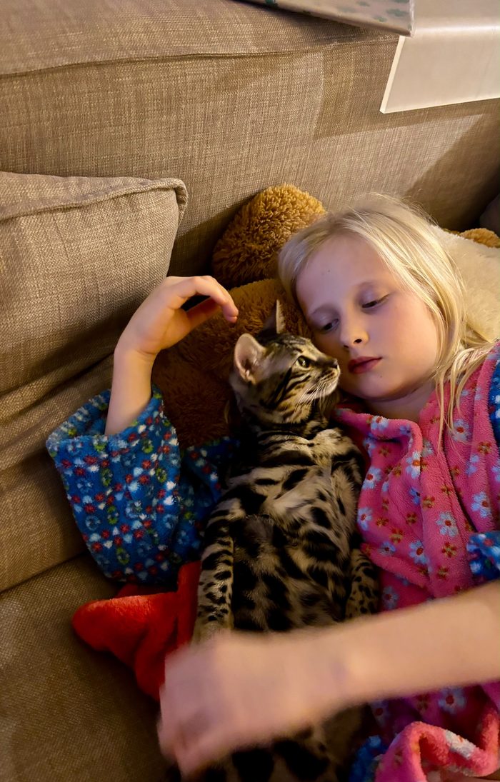 Unsere Tochter und Cleo kuscheln auf dem Sofa